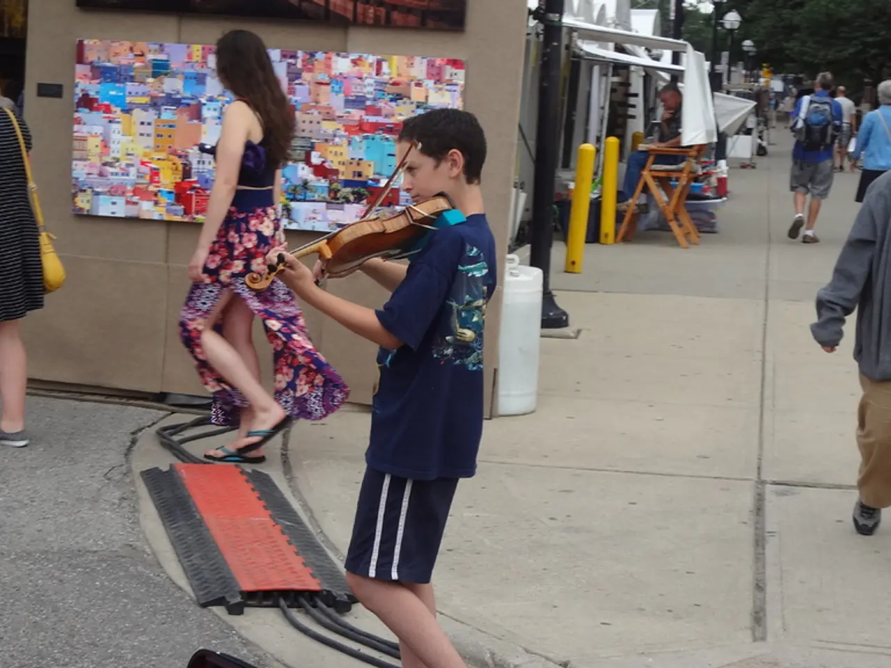 In the image we can see there are many people walking on the street, some of them are standing....