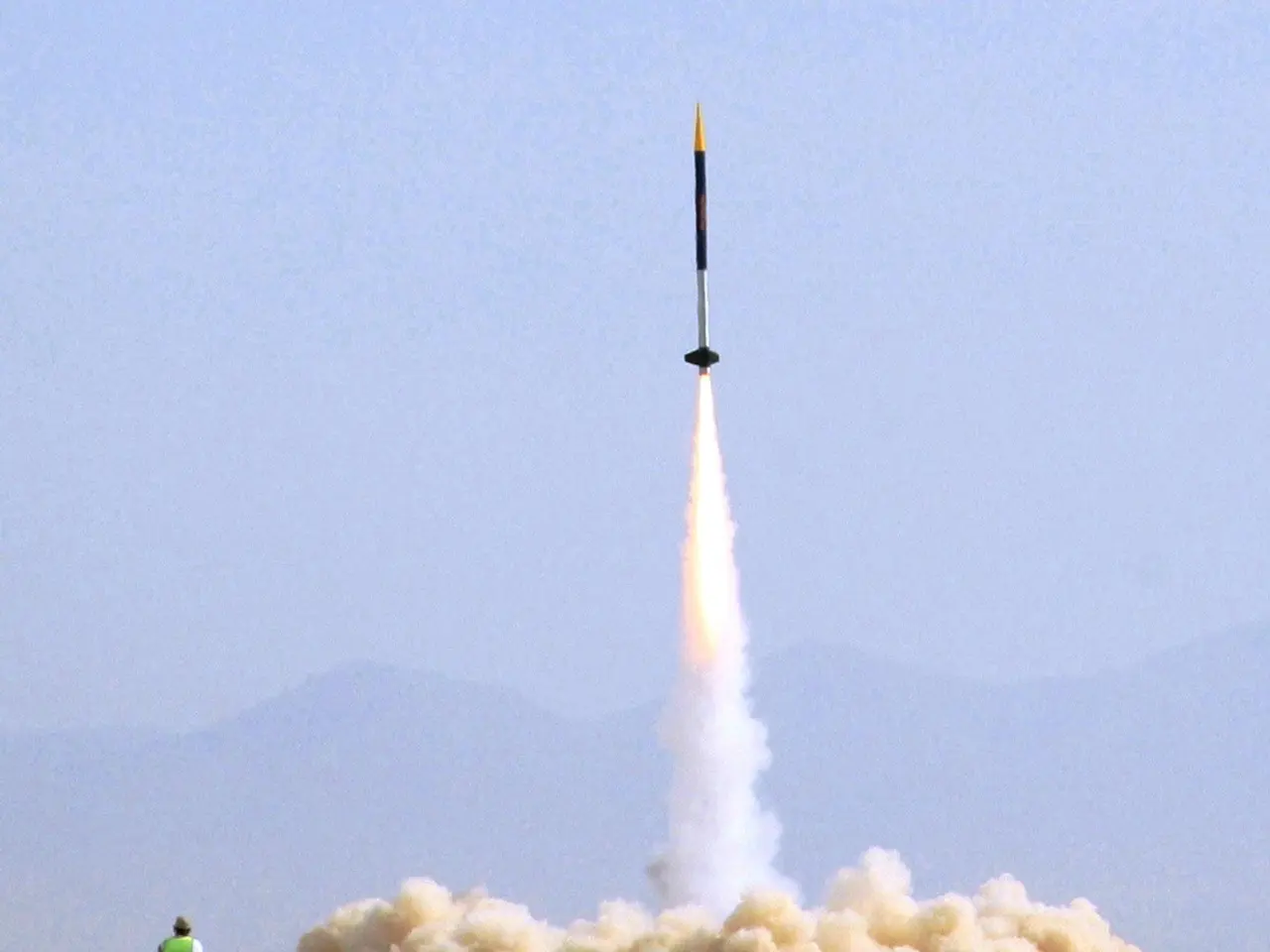 In this image there is a rocket moving into the air. Below to it there is the fire. There is smoke...