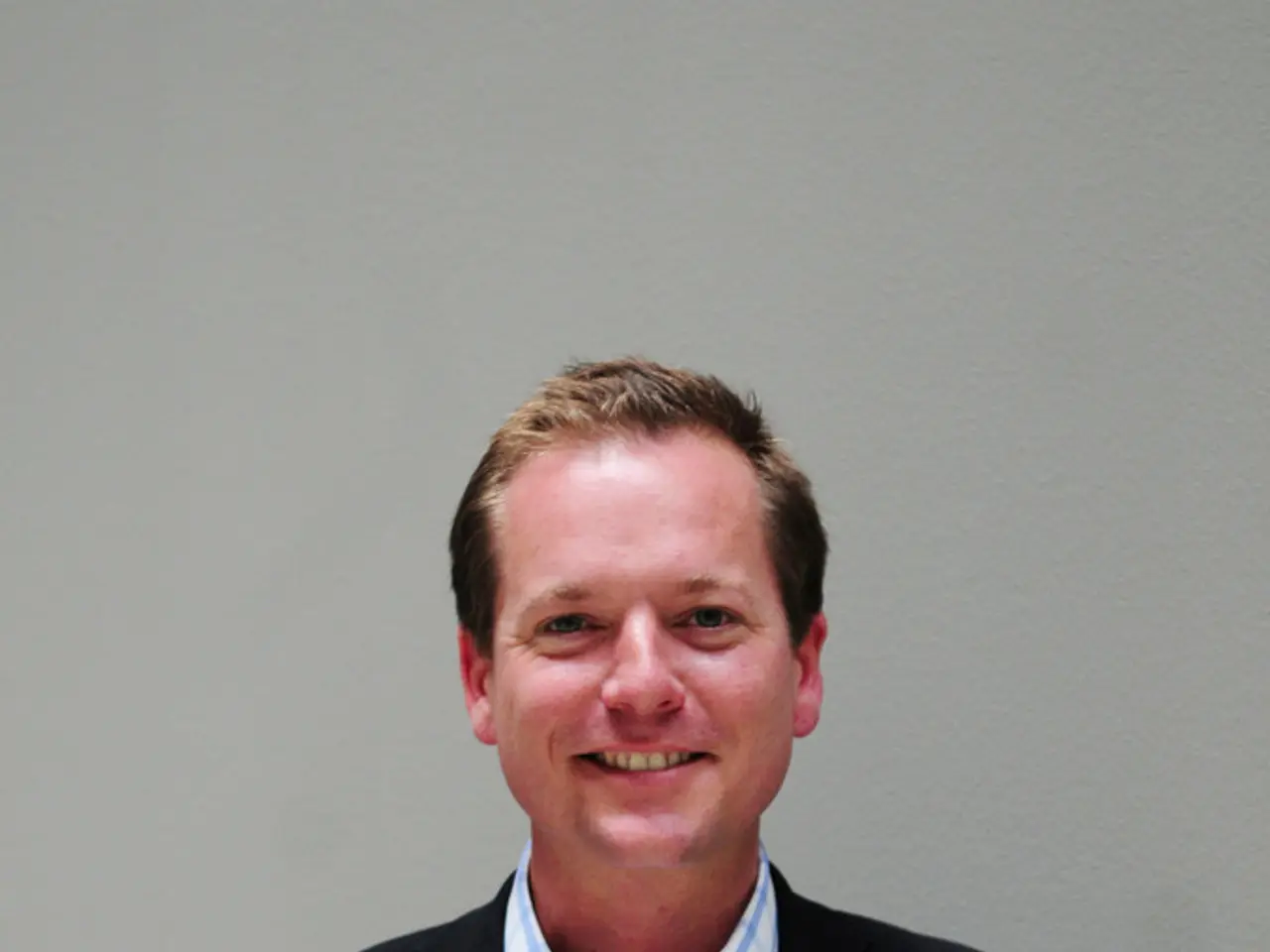 In this picture there is a person wearing black suit is standing and holding a paper which has...