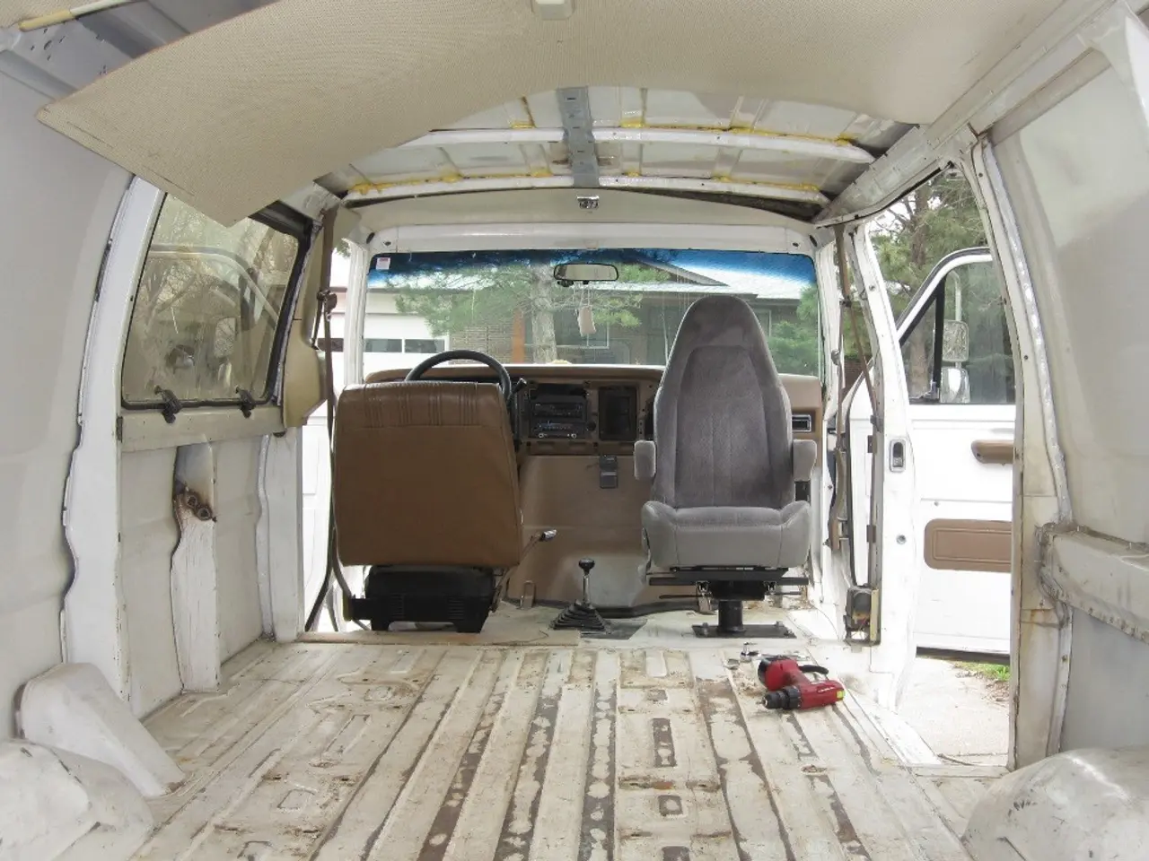 In this picture there is a inside view of the white color van. In the front we can see the seats...