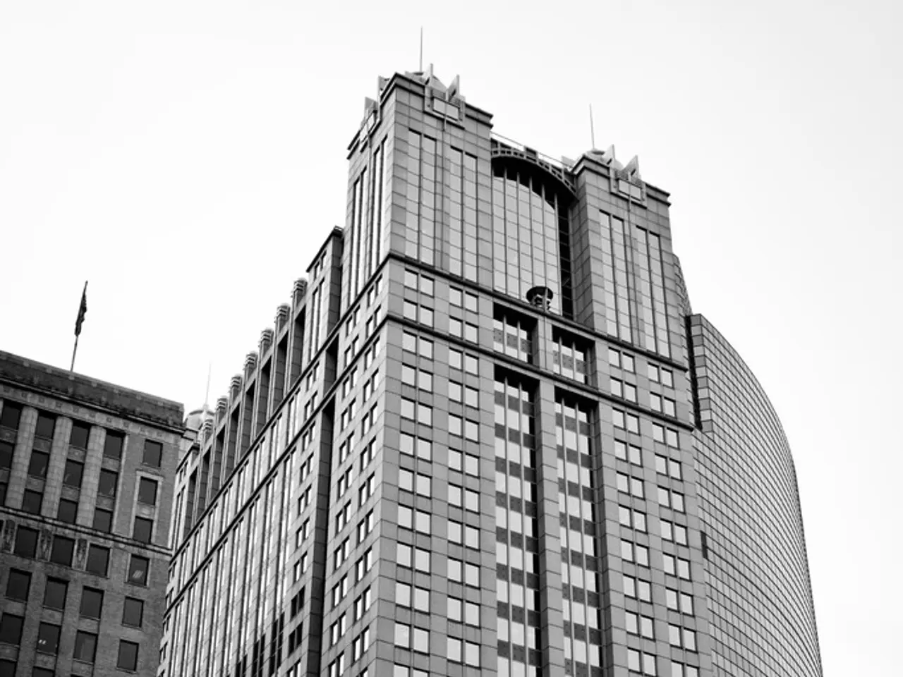 This picture shows couple of tall buildings and we see few of pole lights and a fence and we see a...