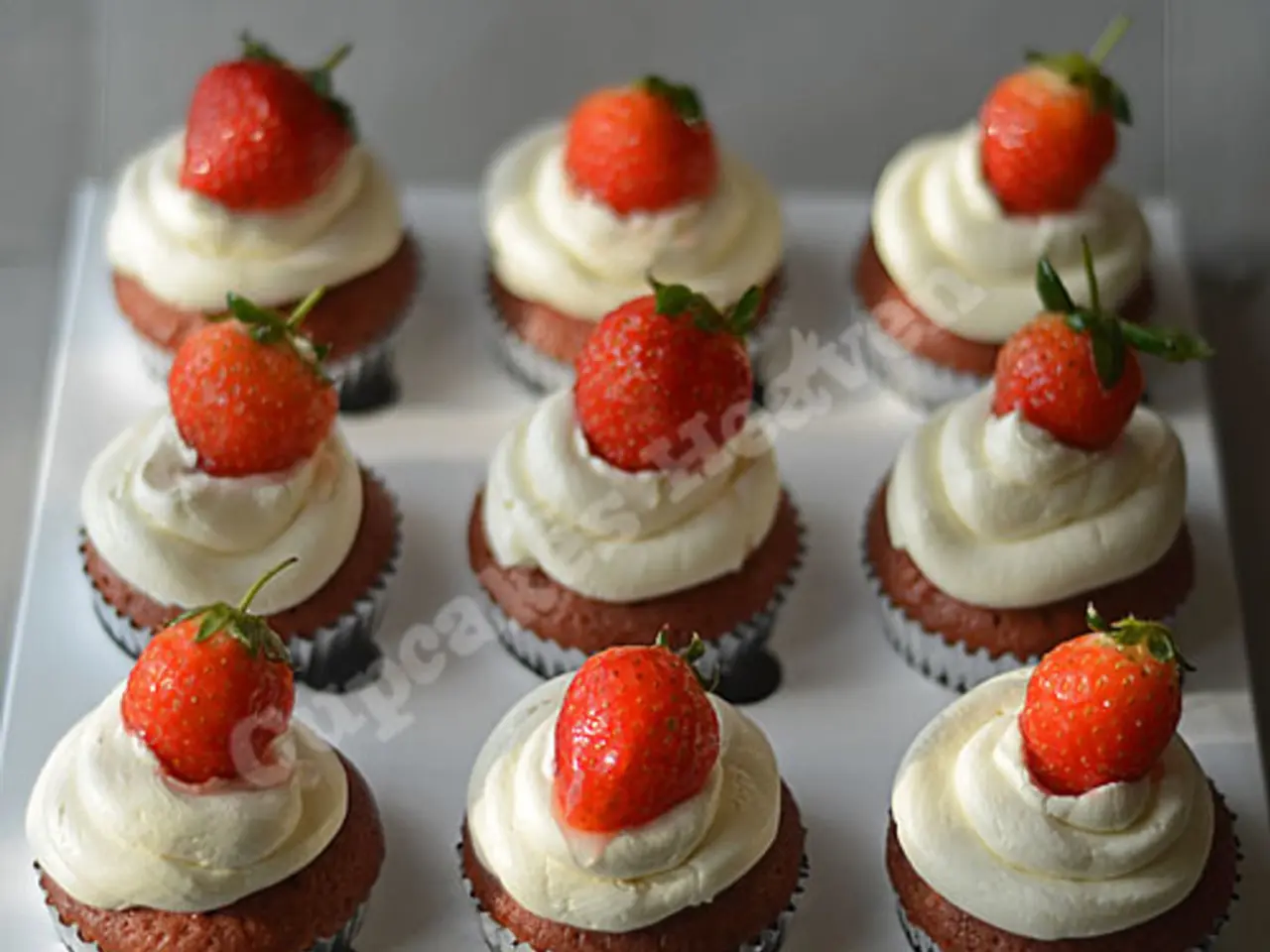 In this image we can see strawberries on the cupcakes on a platform.