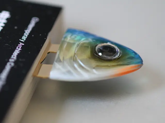 Here on the left we can see a book and there is a metal object with fish logo to it on a platform.