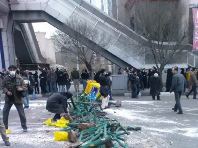 This picture shows few buildings and we see couple of trees and few people standing and we see a...