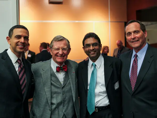 In this image there are people standing. In the foreground there are four men standing. They are...