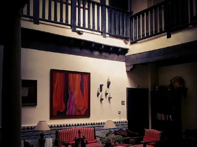 In this picture there is a lamp, sofa , chair , frame , bottles on the wooden plank, books in the...