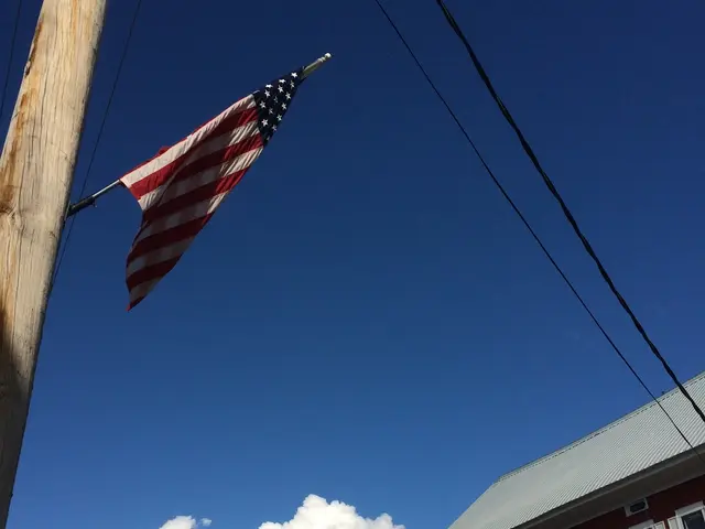 In this image we can see a house with roof and windows. We can also see some wires and a signboard...