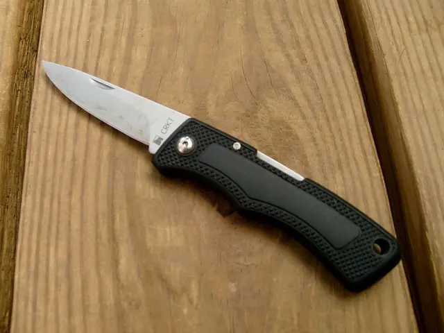 In this image there is a knife which is on the brown colour surface