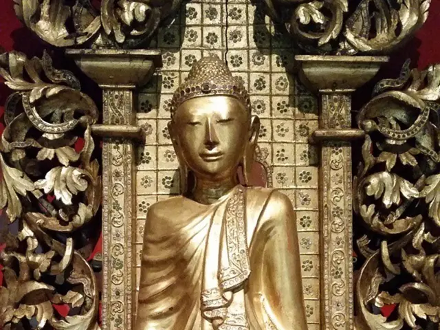 In this image there is a sculpture, and in the background there is a gold color design.